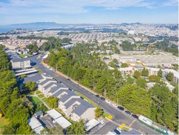 an aerial view of a neighborhood with cars on a road and trees and a city  at Skyline Heights LLC, California